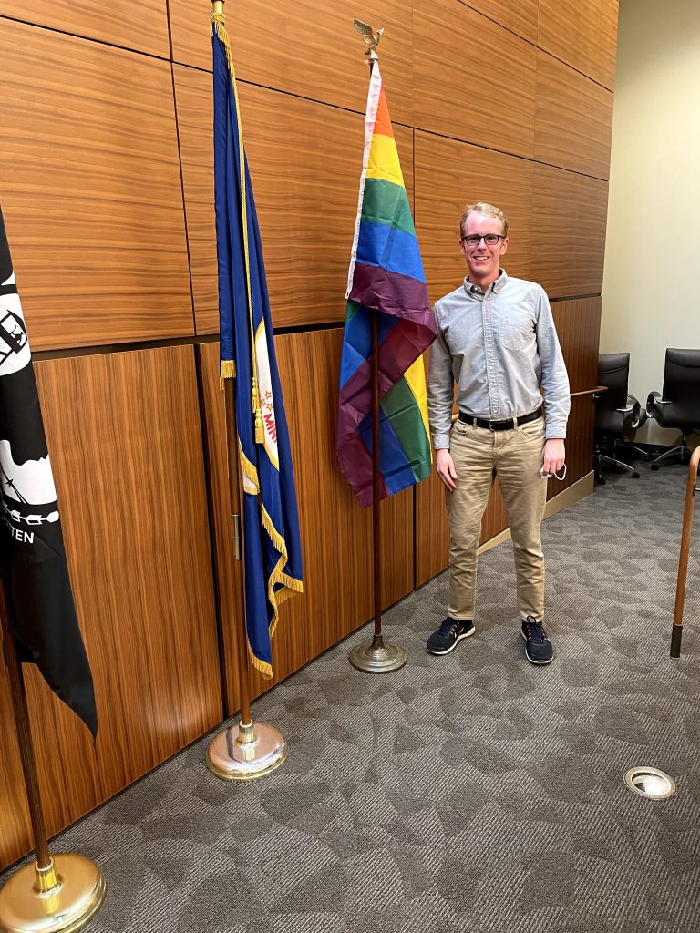 Sean posing next to pride flag