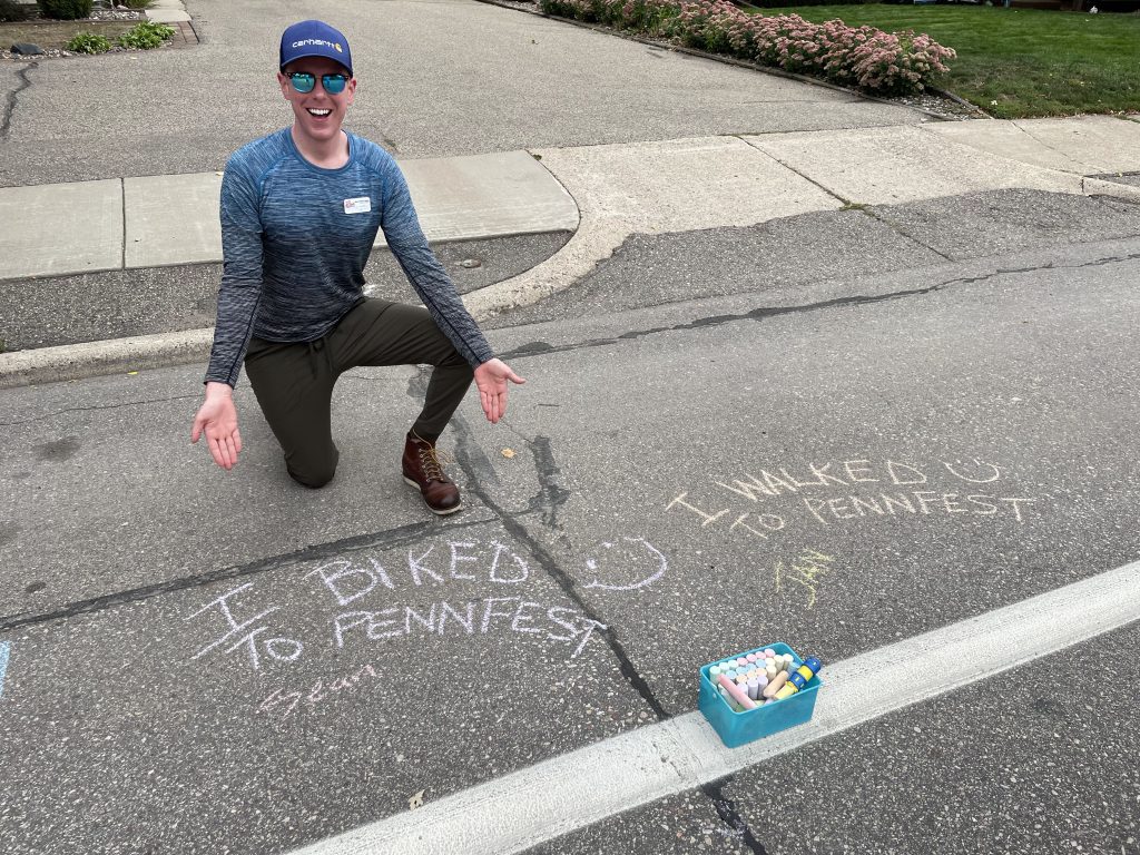 Sean at Penn Fest 2023 next to sidewalk chalk saying I biked to PennFest